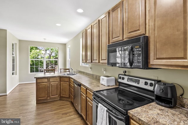 kitchen featuring sink, light hardwood / wood-style flooring, kitchen peninsula, stainless steel appliances, and a chandelier