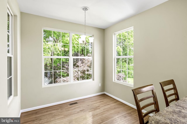 unfurnished dining area featuring a notable chandelier and light wood-type flooring