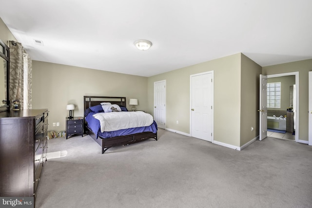 bedroom featuring ensuite bath and light colored carpet