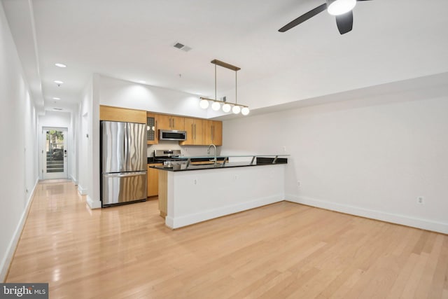 kitchen featuring kitchen peninsula, light wood-type flooring, stainless steel appliances, ceiling fan, and hanging light fixtures