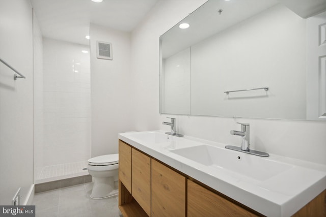 bathroom with tile patterned floors, vanity, toilet, and a tile shower