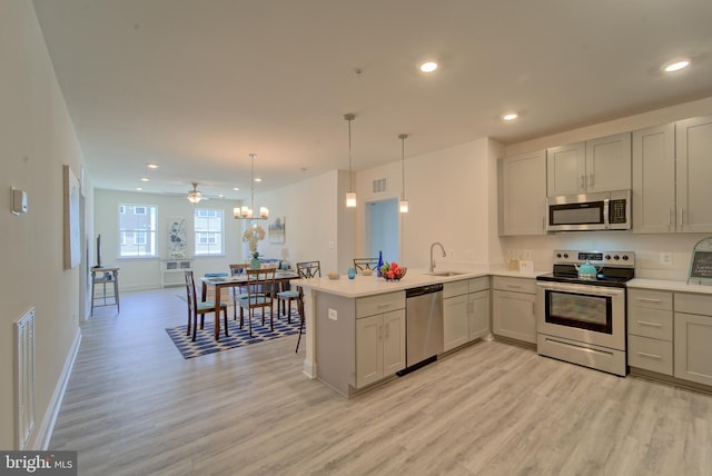 kitchen featuring ceiling fan, sink, hanging light fixtures, kitchen peninsula, and appliances with stainless steel finishes