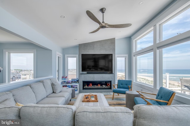 living room with a large fireplace, ceiling fan, and lofted ceiling