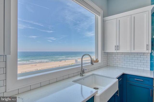 kitchen featuring a beach view, sink, a water view, and plenty of natural light