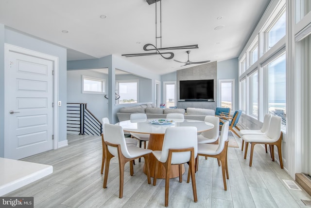 dining room featuring ceiling fan, a healthy amount of sunlight, light wood-type flooring, and vaulted ceiling