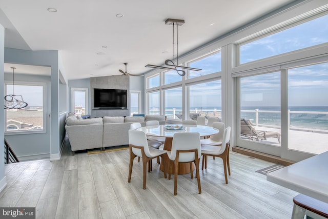 dining space with plenty of natural light, vaulted ceiling, ceiling fan with notable chandelier, and light hardwood / wood-style flooring