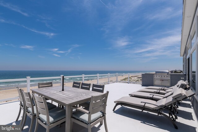 view of patio featuring area for grilling, a water view, and a view of the beach