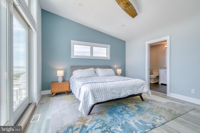 bedroom featuring hardwood / wood-style floors, lofted ceiling, and connected bathroom