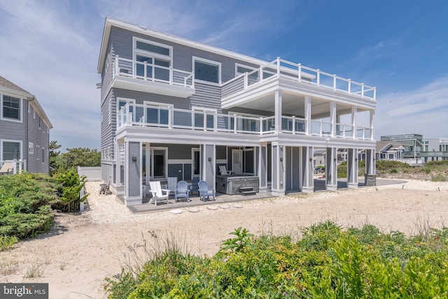 back of house with a patio area, a balcony, and a hot tub