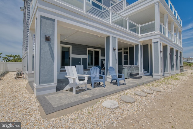 back of property with a patio area, a balcony, and a hot tub