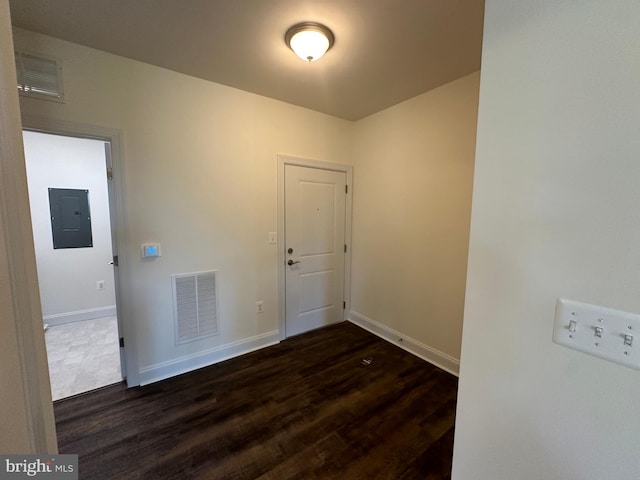 empty room with dark hardwood / wood-style floors and electric panel