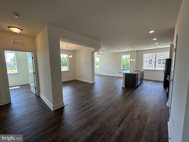 kitchen featuring sink, an island with sink, hanging light fixtures, and dark hardwood / wood-style floors