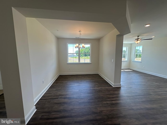 unfurnished dining area featuring dark hardwood / wood-style flooring and ceiling fan with notable chandelier