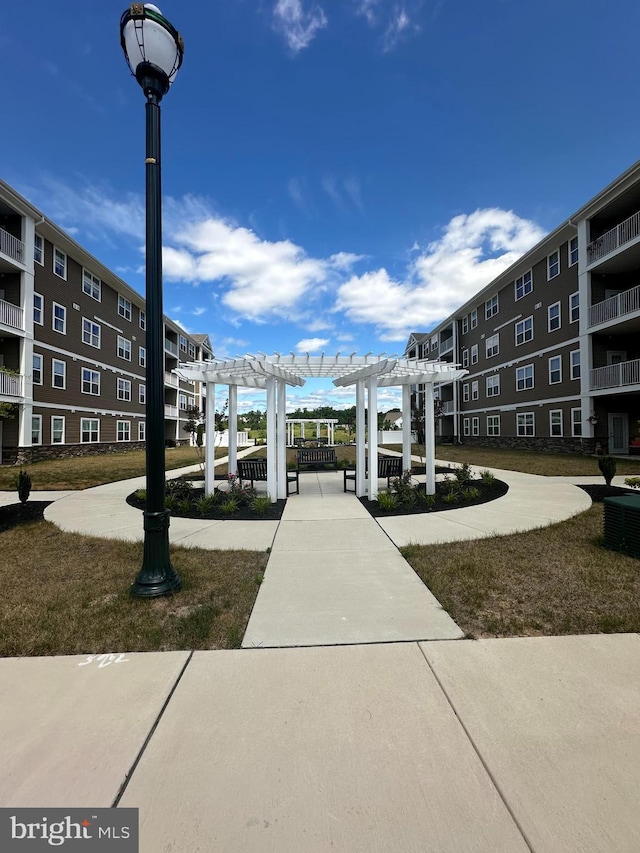 view of property's community featuring a pergola and a lawn