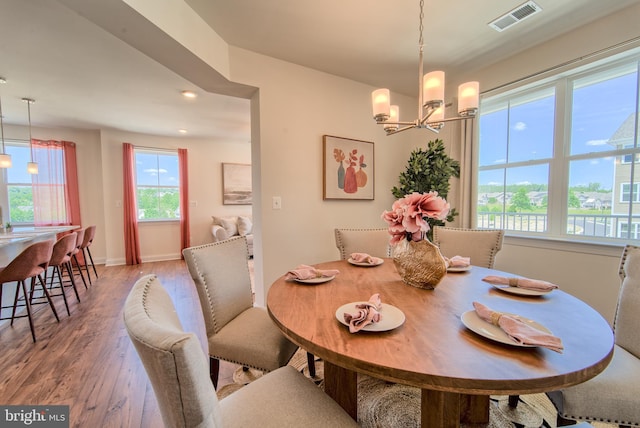 dining area with a wealth of natural light, a chandelier, and hardwood / wood-style flooring