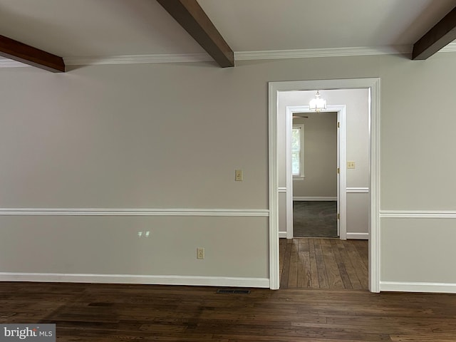 spare room featuring beamed ceiling and dark wood-type flooring