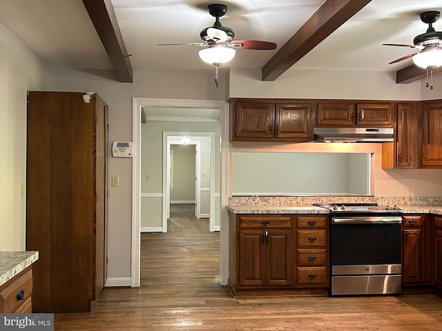 kitchen featuring stainless steel range, beamed ceiling, ceiling fan, and light hardwood / wood-style floors