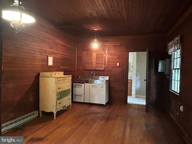 interior space with dark wood-type flooring, a baseboard heating unit, wood walls, dishwashing machine, and wooden ceiling