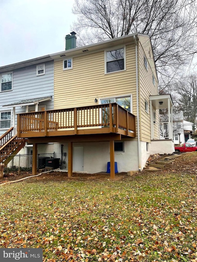 rear view of house with central AC unit, a deck, and a yard