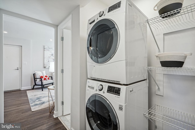 clothes washing area featuring stacked washer / dryer and dark hardwood / wood-style flooring