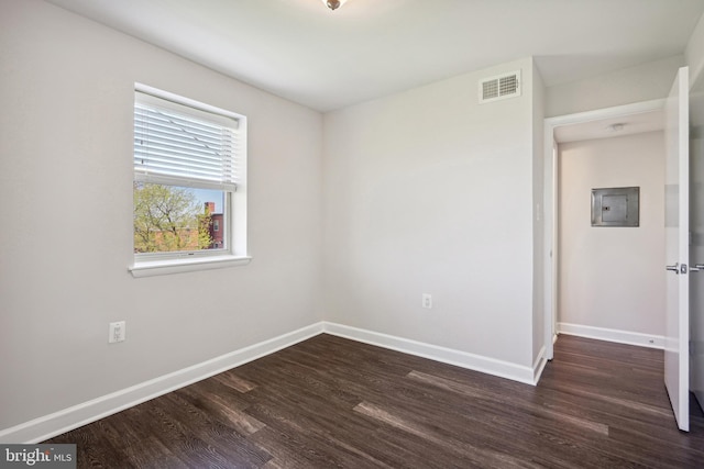 empty room featuring electric panel and dark hardwood / wood-style flooring