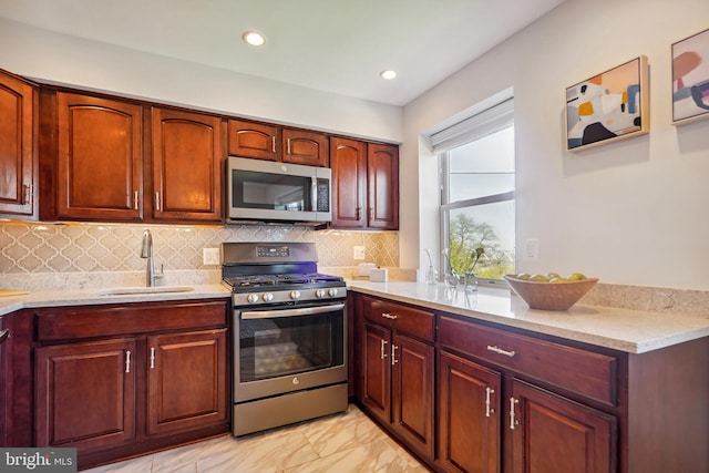 kitchen featuring light stone counters, stainless steel appliances, tasteful backsplash, and sink