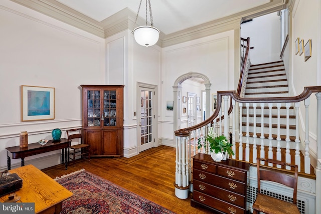 foyer with dark wood-type flooring, a towering ceiling, and decorative columns