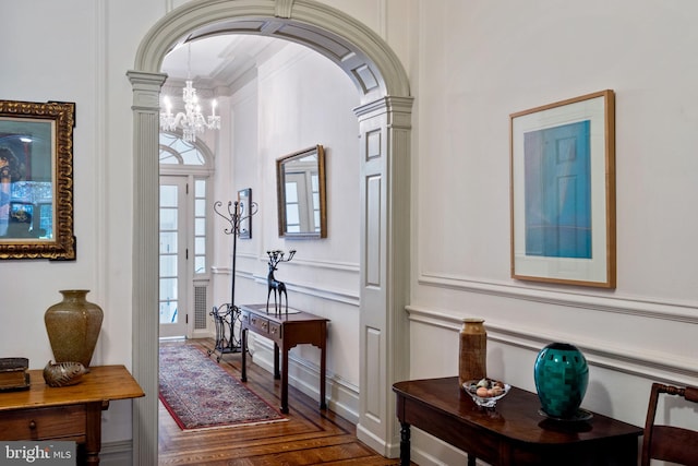 entrance foyer featuring an inviting chandelier, crown molding, dark hardwood / wood-style floors, and decorative columns