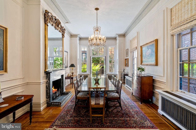 dining room featuring radiator, a healthy amount of sunlight, ornamental molding, and a premium fireplace