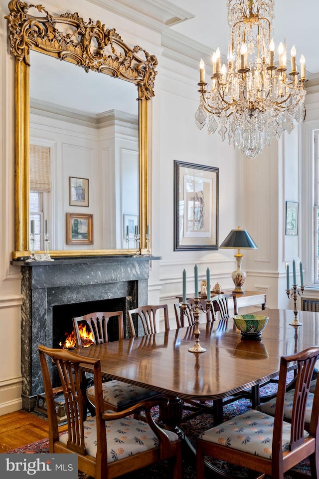 dining room with a premium fireplace, an inviting chandelier, ornamental molding, and wood-type flooring