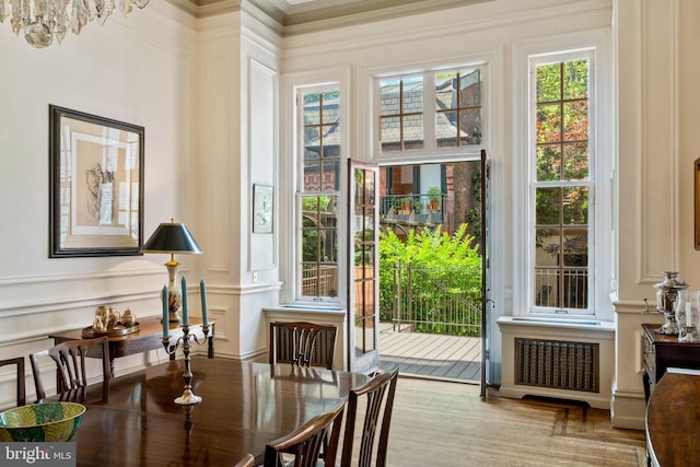 entryway with a notable chandelier, light hardwood / wood-style flooring, crown molding, and radiator heating unit