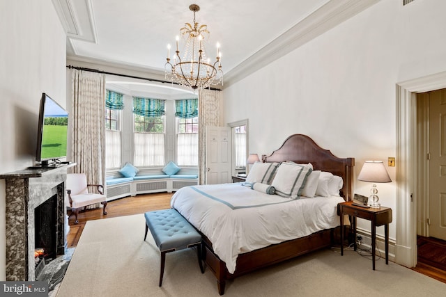 bedroom featuring crown molding, hardwood / wood-style flooring, an inviting chandelier, and a fireplace