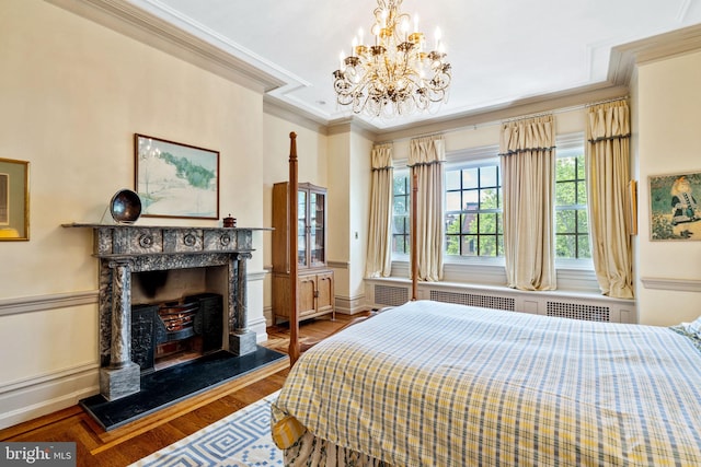 bedroom featuring radiator heating unit, a notable chandelier, a premium fireplace, wood-type flooring, and crown molding