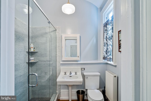 bathroom with a shower with door, radiator heating unit, and toilet