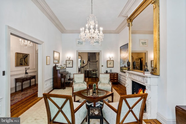 living area with an inviting chandelier, a premium fireplace, crown molding, and light wood-type flooring