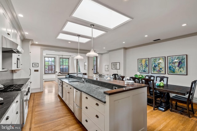 kitchen featuring extractor fan, sink, a center island with sink, and white cabinets