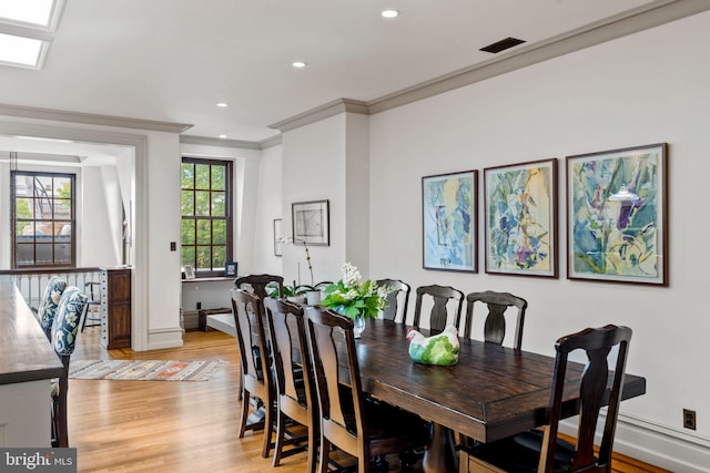 dining space with crown molding and light wood-type flooring