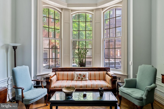 living area featuring crown molding, wood-type flooring, and plenty of natural light