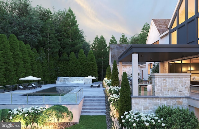 yard at dusk featuring a pool and a patio area