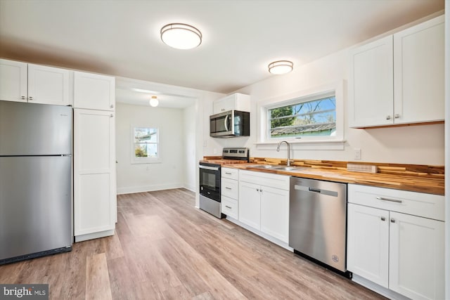 kitchen featuring wood counters, white cabinetry, sink, and appliances with stainless steel finishes