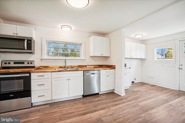 kitchen with sink, stainless steel appliances, light hardwood / wood-style flooring, wooden counters, and white cabinets