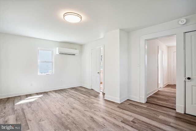 interior space with a wall mounted air conditioner and light wood-type flooring