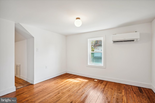 unfurnished room with a wall unit AC and hardwood / wood-style flooring