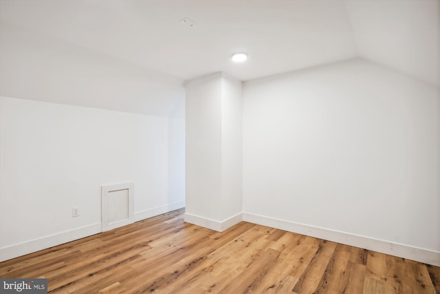 empty room with light wood-type flooring and lofted ceiling