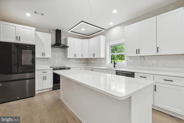 kitchen featuring sink, white cabinets, stainless steel appliances, and wall chimney range hood