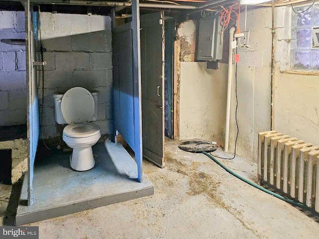 bathroom with electric panel, toilet, radiator, and concrete floors