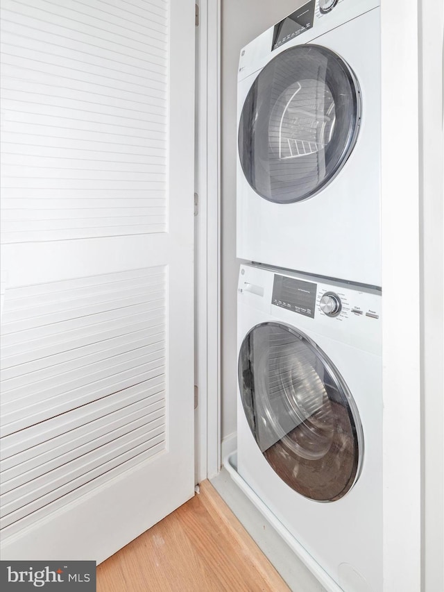 laundry room with hardwood / wood-style floors and stacked washer and clothes dryer