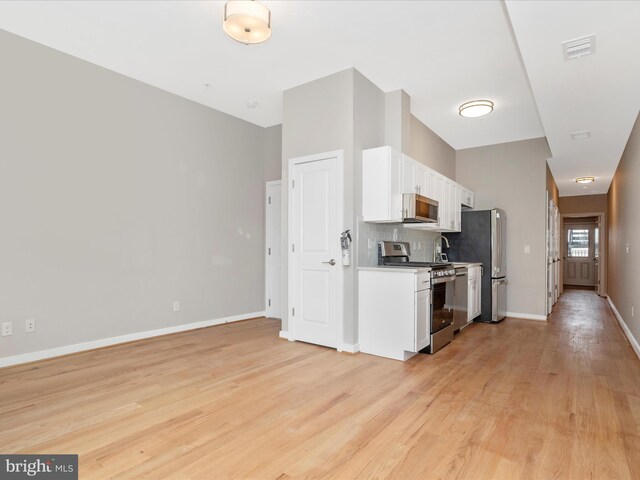 kitchen with light hardwood / wood-style floors, white cabinetry, appliances with stainless steel finishes, and tasteful backsplash