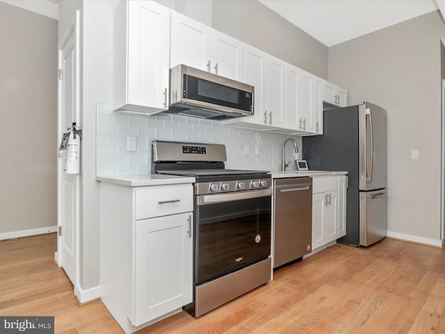 kitchen with light wood-type flooring, white cabinetry, and stainless steel appliances