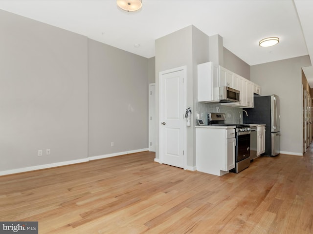 kitchen featuring backsplash, white cabinets, stainless steel appliances, and light wood-type flooring